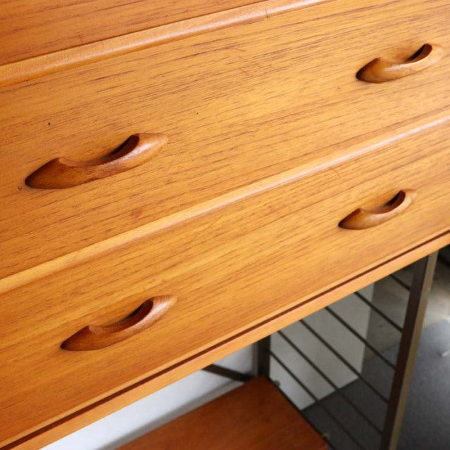 Close-up of vintage teak drawer fronts with curved wooden handles, highlighting mid-century British Ladderax craftsmanship.