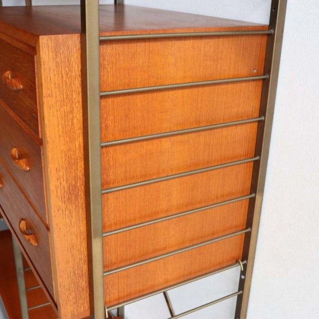 Vintage teak Ladderax unit shelf with six drawers, British mid-century design featuring rich wood grain and brass frame legs.