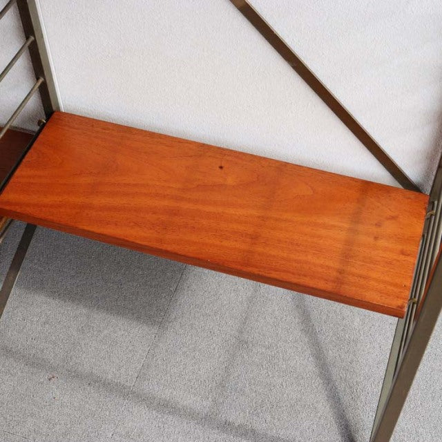 Vintage teak Ladderax shelving unit with British mid-century design, showcasing warm wood grain and slender metal frame legs.