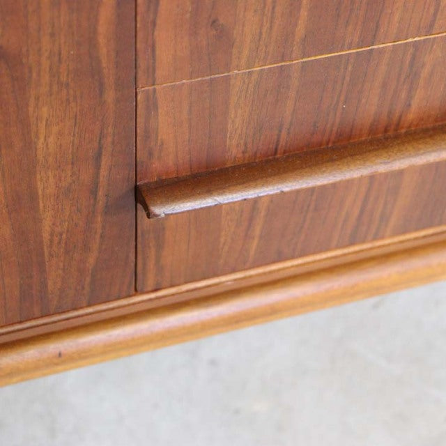 Close-up of vintage teak sideboard drawer with smooth wood grain and sculpted handle, British mid-century design by A.H.