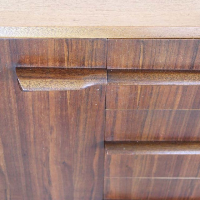 Close-up of vintage teak sideboard with rich wood grain, sculpted British mid-century handles, and smooth finish.