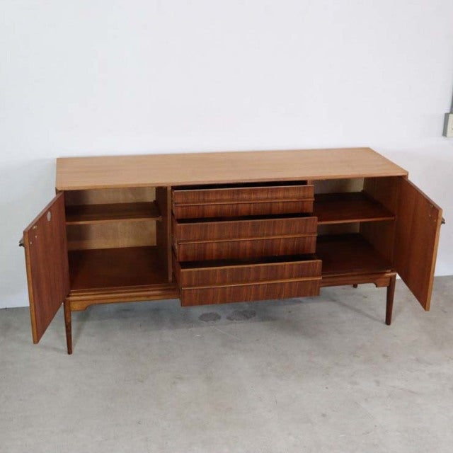 Vintage mid-century teak sideboard by A.H. McIntosh with rich wood grain, three central drawers, and two door cabinets on.