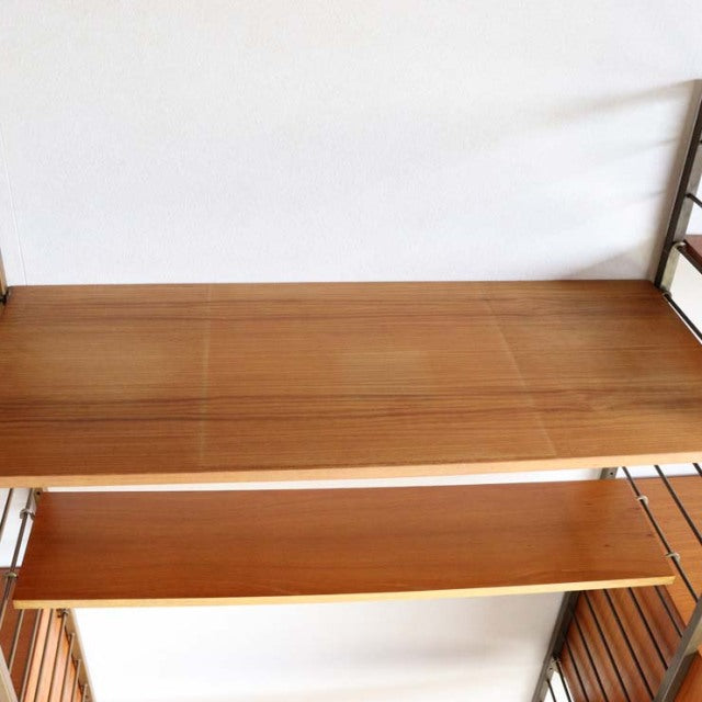 Mid-century British Ladderax shelving unit in warm teak with fine wood grain and clean lines, featuring ladder-style side.