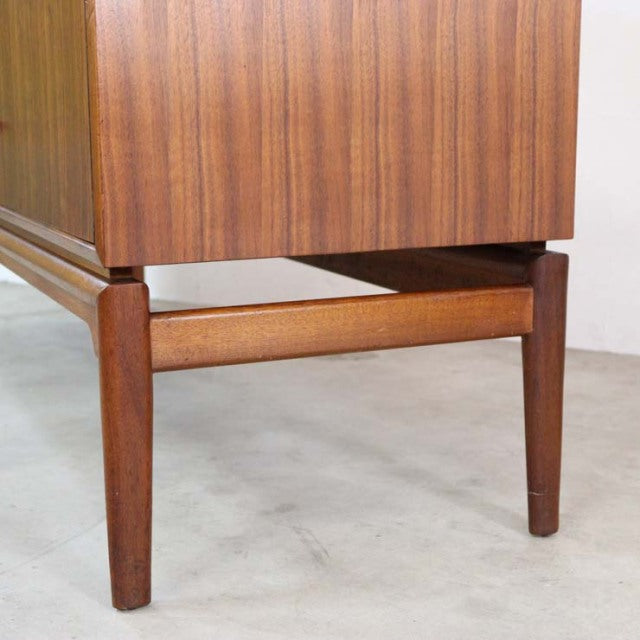 Close-up of mid-century vintage British teak sideboard leg with clean lines and rich wood grain.