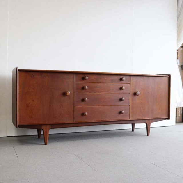 Mid-century vintage teak sideboard with five central drawers, rounded wooden knobs, smooth wood grain, tapered legs, British .