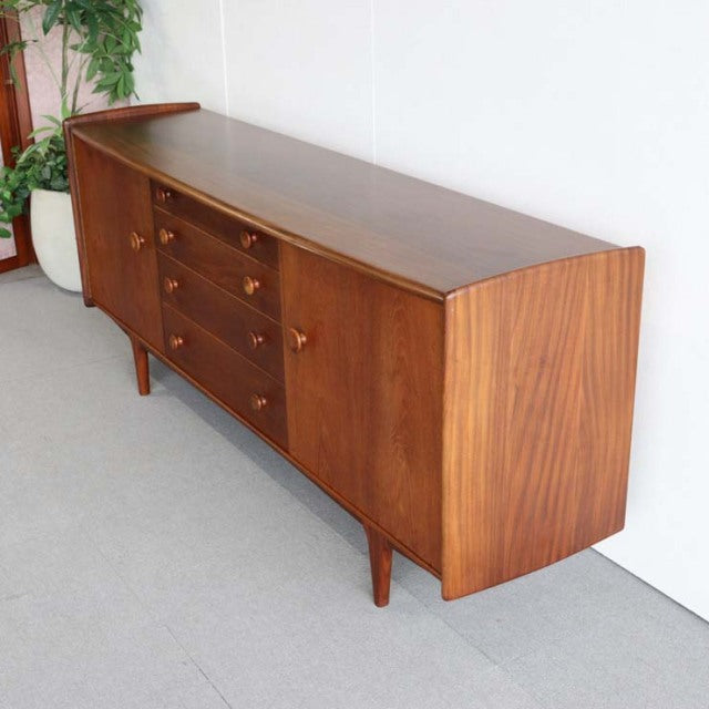 Mid-century British teak sideboard with rich wood grain, tapered legs, and multiple drawers and cabinet doors from Denmark.