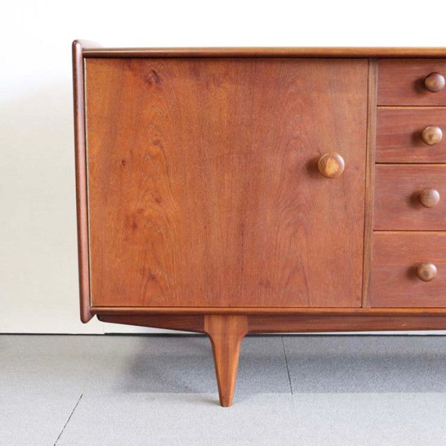 Vintage teak sideboard with warm wood grain, rounded edges, and tapered mid-century British legs.