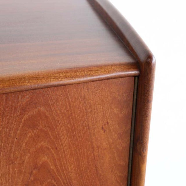 Mid-century teak sideboard corner with smooth rounded edges and warm wood grain, British-Danish vintage style.