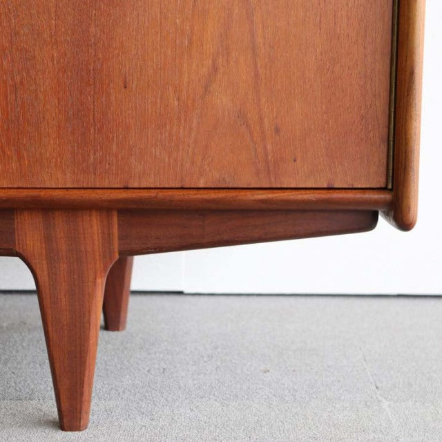 Mid-century British vintage teak sideboard corner showcasing rich wood grain and tapered legs with smooth rounded edges.