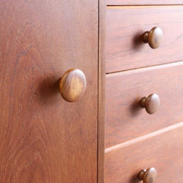 Vintage teak sideboard drawer close-up showing smooth wood grain and rounded wooden knobs with mid-century British and.