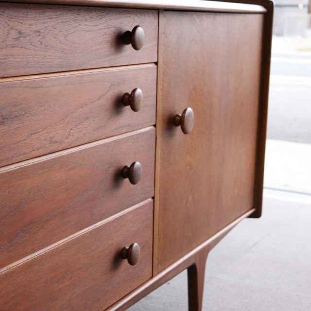 Mid-century British vintage teak sideboard by Younger with wood grain, round knobs, and tapered legs from Denmark.