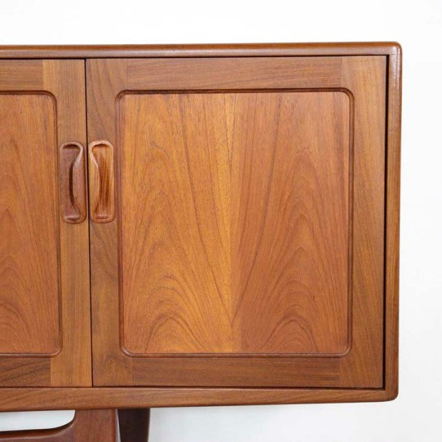 Mid-century British G-Plan Fresco teak sideboard door panel with smooth wood grain and curved handles.