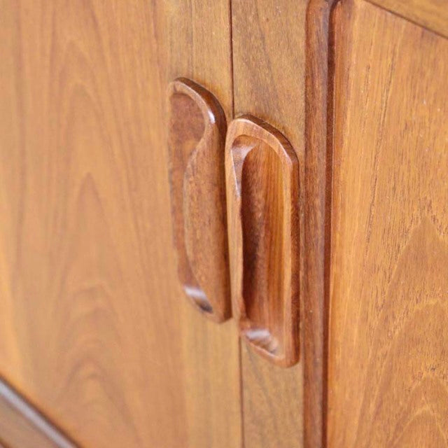 Close-up of vintage teak G-PLAN Fresco sideboard door handles showing warm wood grain and smooth mid-century British design.