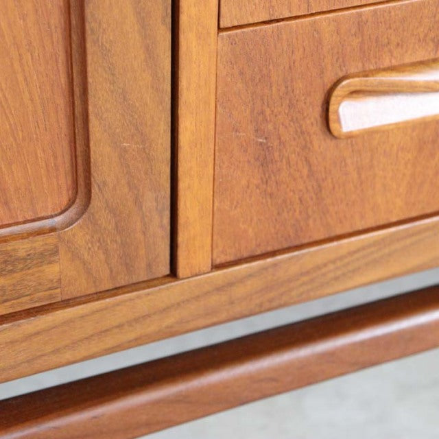 Close-up of vintage teak mid-century British G-Plan Fresco sideboard showing wood grain, smooth rounded drawer handle, and.