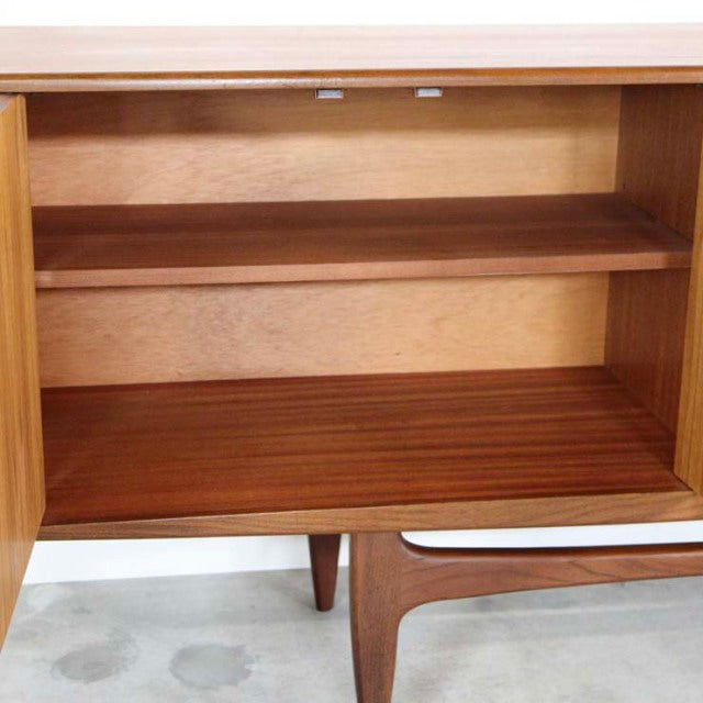 Mid-century British vintage G-Plan Fresco sideboard in teak with visible wood grain, tapered legs, and open shelf interior.