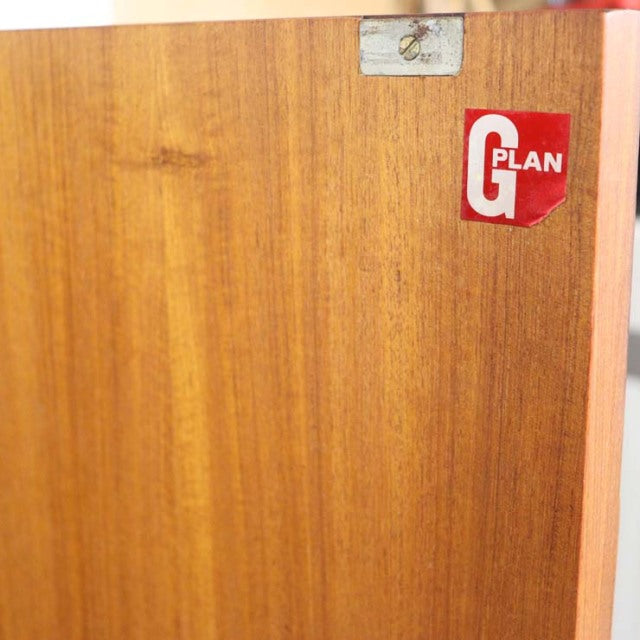 Close-up of vintage teak wood grain on British mid-century G-Plan Fresco sideboard panel with red logo label.