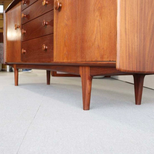 Mid-century British vintage teak sideboard with rich wood grain, tapered legs, and rounded edges from Denmark.
