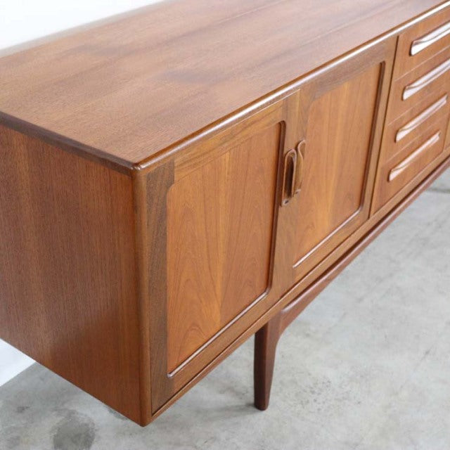Vintage G-PLAN teak sideboard with smooth wood grain, mid-century British design, slender tapered legs, and curved door.