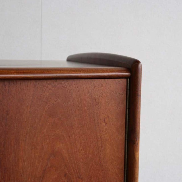 Vintage teak sideboard corner with smooth rounded British mid-century design, showcasing rich wood grain and slender legs.
