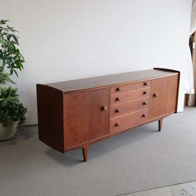 Vintage teak sideboard by Volnay, British mid-century design with clean wood grain, tapered legs, and four drawers centered.