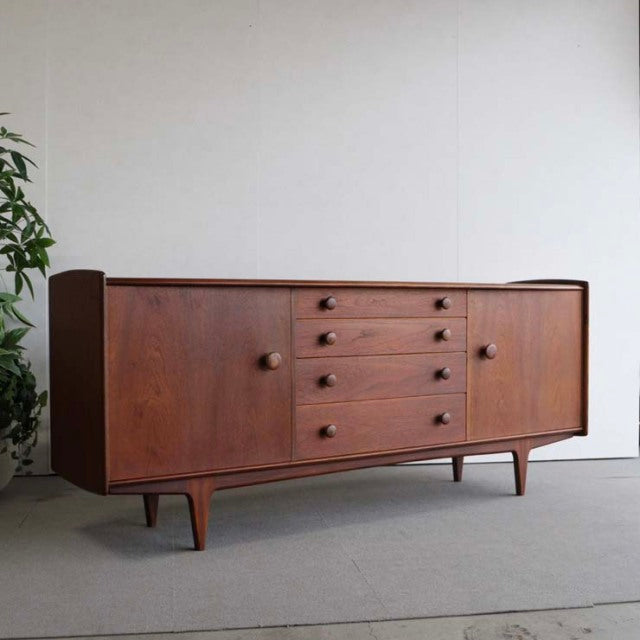 Mid-century British vintage teak sideboard by Younger, featuring smooth wood grain, four central drawers with round knobs,.