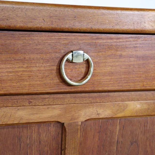 Close-up of vintage British Nathan teak sideboard drawer with brass ring pull and rich wood grain detailing.