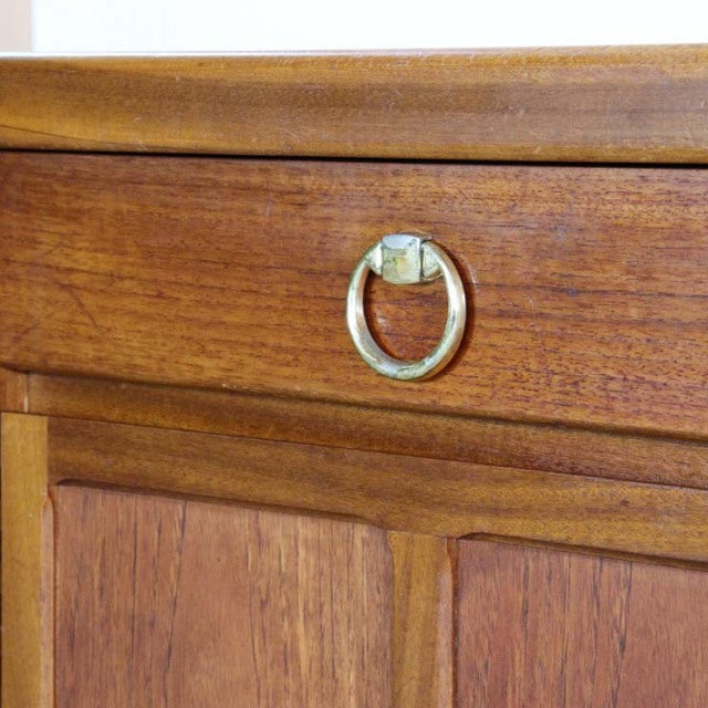 Close-up of British vintage Nathan teak sideboard drawer with brass ring pull, showcasing warm wood grain and mid-century.