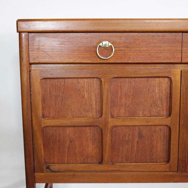Vintage teak Nathan mid-century British sideboard with rich wood grain, brass ring pull, and paneled door design.