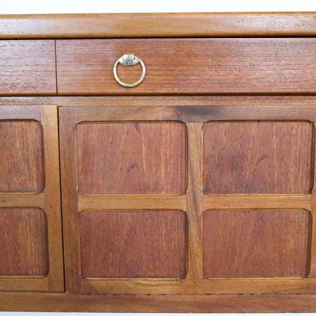 Mid-century British vintage teak sideboard by Nathan with rich wood grain, brass ring handle, and paneled doors.