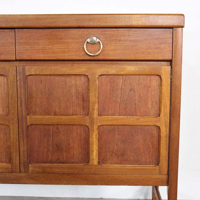 Mid-century British vintage teak sideboard by Nathan with rich wood grain, brass ring pull, and tapered legs.