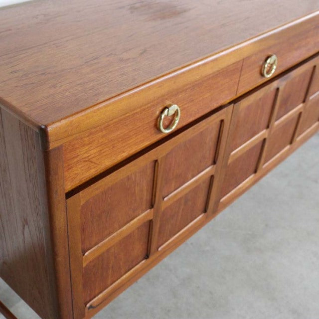 Mid-century British vintage teak sideboard by Nathan with brass ring handles and geometric panel doors.