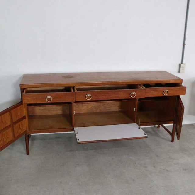 Mid-century British teak sideboard by Nathan with visible wood grain, tapered legs, three drawers, and dual cabinets.