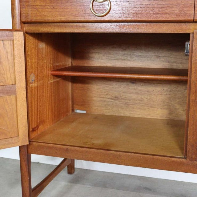 Mid-century British Nathan teak sideboard open cabinet showing rich wood grain, clean interior, and slender legs.
