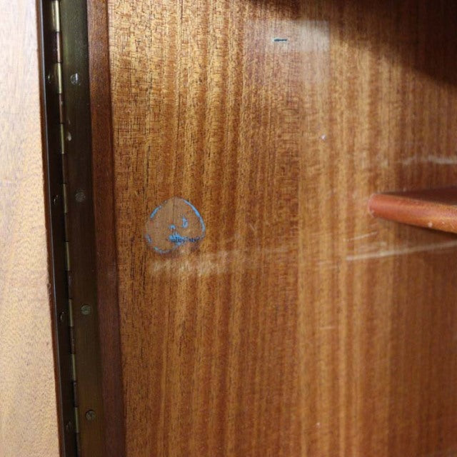 Close-up of vintage British Nathan teak sideboard interior showing rich wood grain and brass hinge detail, mid-century.