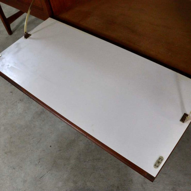 Mid-century British teak sideboard top panel showing smooth white laminate surface with natural wood grain edge and brass.