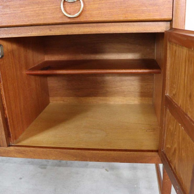 Open teak cabinet door revealing mid-century vintage British sideboard interior with smooth wood grain and shelf.