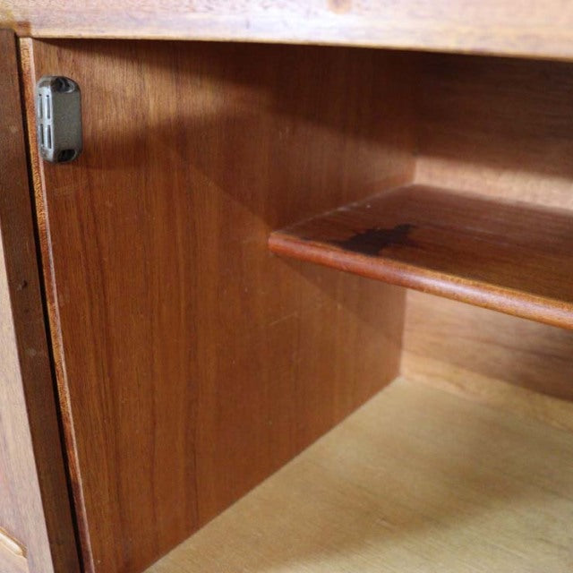 Interior view of vintage British mid-century teak sideboard showing smooth wood grain, adjustable shelf, and sturdy hinge.