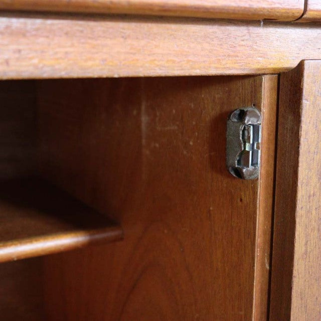 Close-up of vintage British mid-century teak sideboard door showing rich wood grain and metal latch detail.