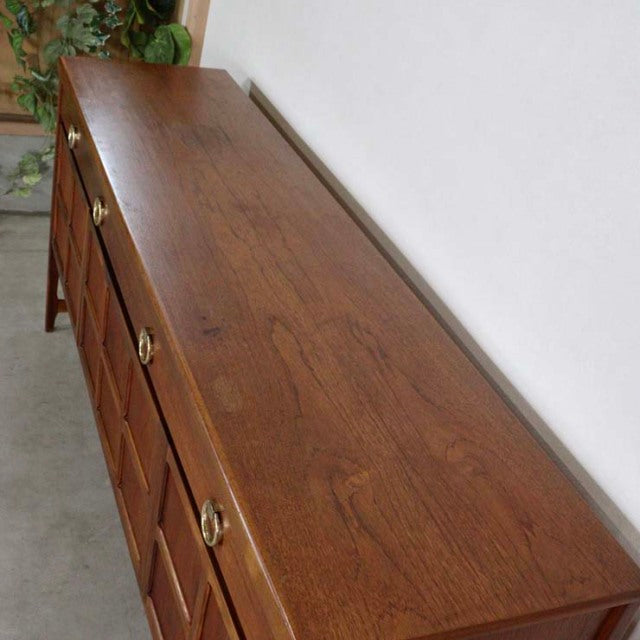 Mid-century British teak sideboard by Nathan with rich wood grain, brass pulls, and slender legs.
