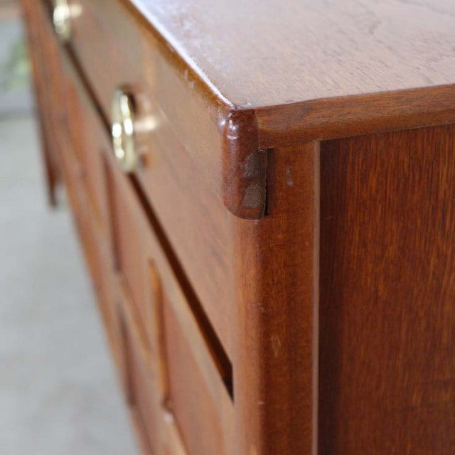 Close-up of vintage British teak sideboard corner showing rich wood grain, smooth finish, and precise mid-century joinery.
