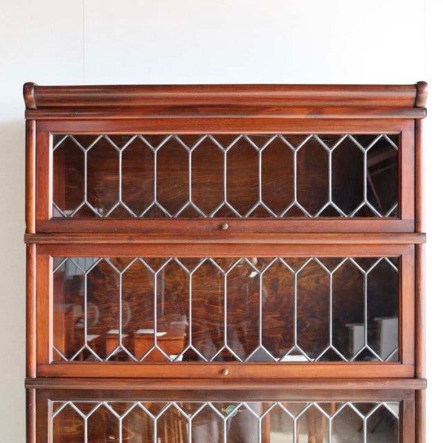 Vintage mid-century teak Globe Wernicke glass bookcase with British design, intricate leaded glass panels, and rich wood.
