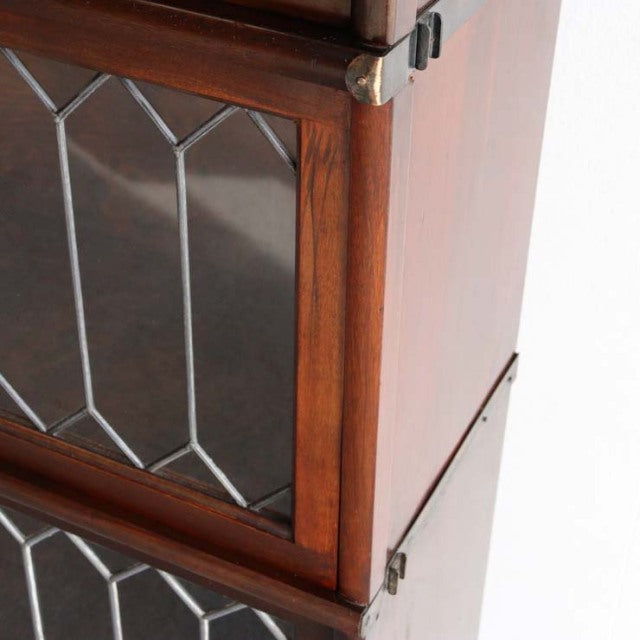 Vintage British Globe Wernicke teak glass bookcase with geometric leaded glass and brass corner accents.