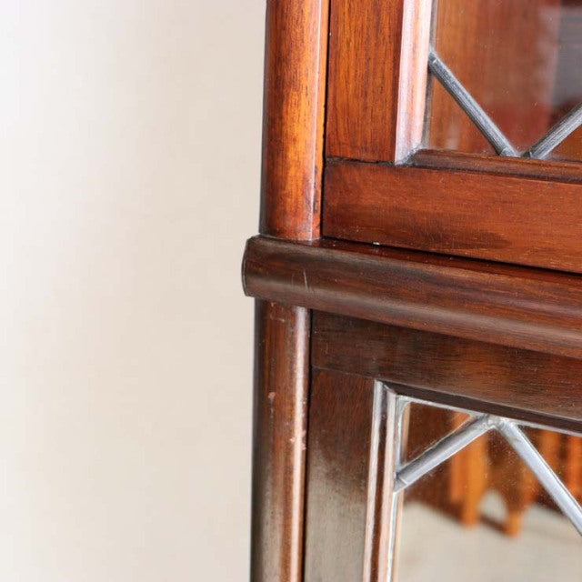 Close-up of vintage teak Globe Wernicke glass bookcase corner with mid-century British craftsmanship and detailed wood grain.