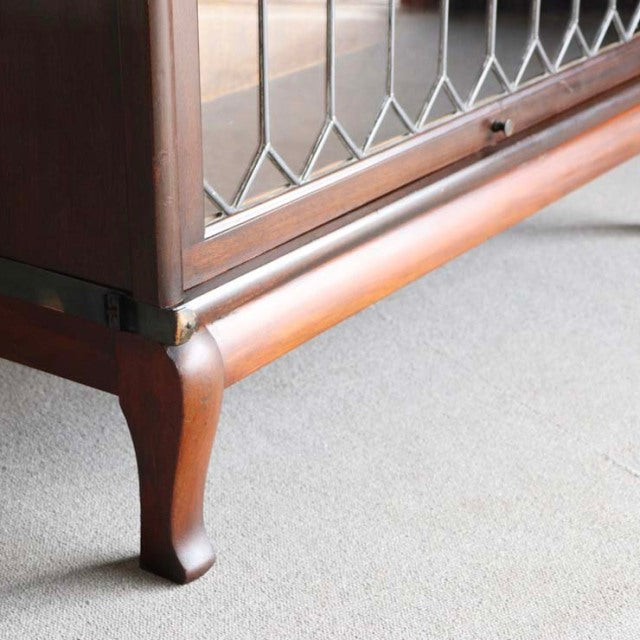 Vintage teak Globe-Wernicke British glass bookcase with mid-century curved legs and leaded glass panels.
