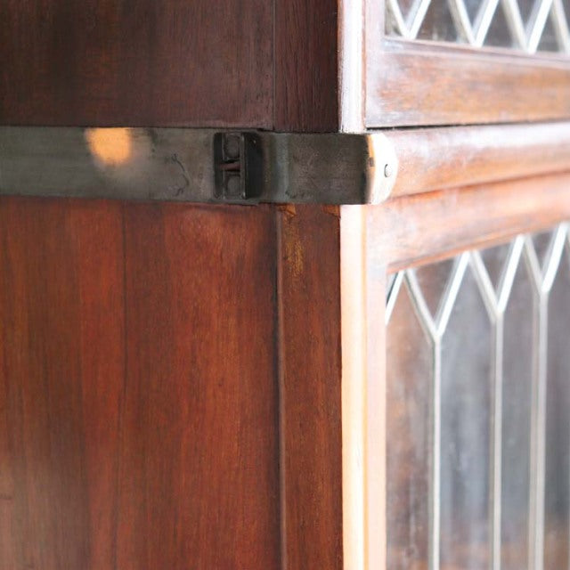 Close-up of vintage teak Globe Wernicke glass bookcase corner with mid-century British craftsmanship and aged wood grain.