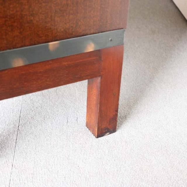 Close-up of vintage teak wood leg with visible grain and metal trim on British mid-century Globe Wernicke glass bookcase.