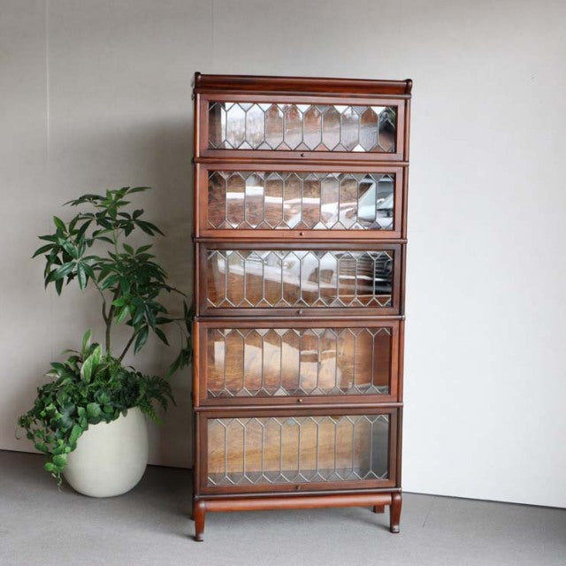 Vintage British Globe-Wernicke teak glass bookcase with five stacked sections and intricate wood grain detailing,.