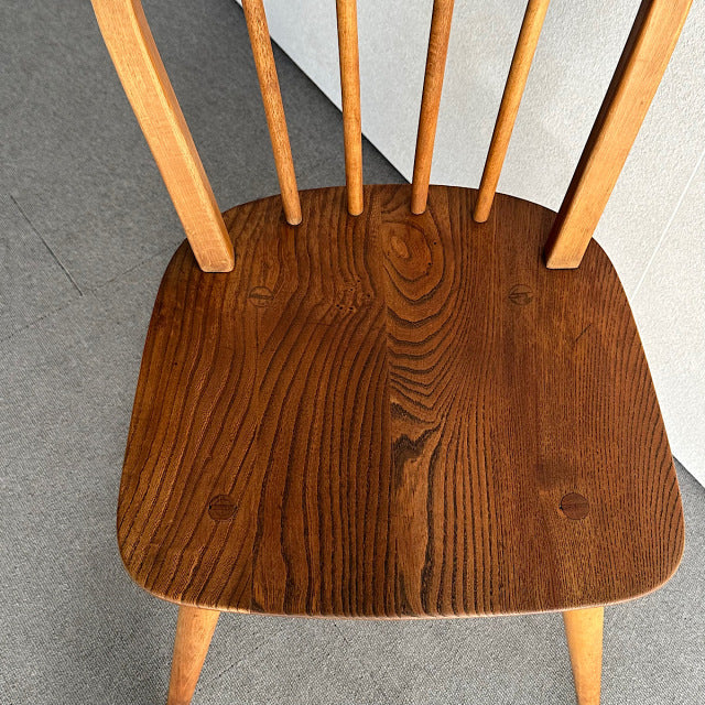 Vintage British mid-century Ercol hoop back chair in rich teak with visible wood grain and slender spindled legs.
