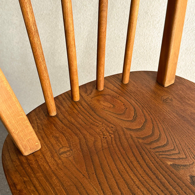 Close-up of vintage British mid-century teak dining chair seat and curved hoop back with four vertical spindles, smooth wood .