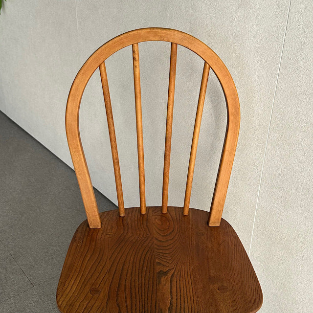 Vintage mid-century British Ercol dining chair in teak with curved hoop back and four slender vertical spindles, showcasing.